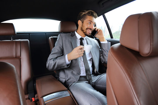 Young businessman having a coffee in his car