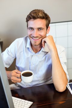 Portrait of young man holding coffee cup in office