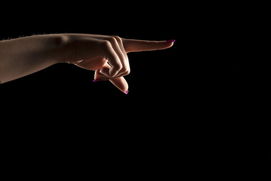 woman's hand on a dark background, showing direction
