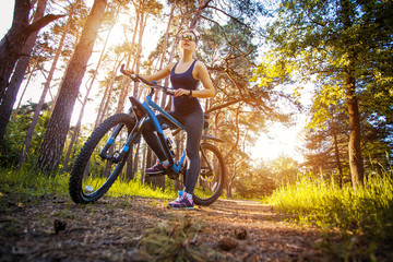 Naklejka premium woman cyclist rides in the forest on a mountain bike.