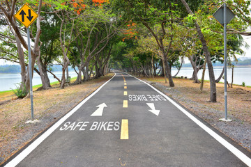 Obraz premium Safety concept, Safe bikes words with white arrow sign marking on road surface in the park for giving directions