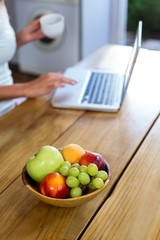 Fruits on table with woman working on laptop