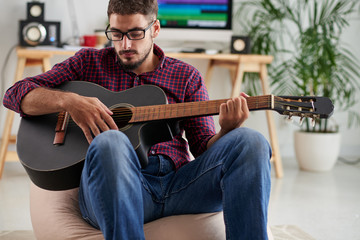 Obraz premium Handsome young man in glasses playing guitar