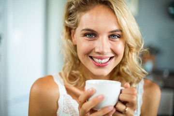 Close-up portrait of smiling young woman having coffee