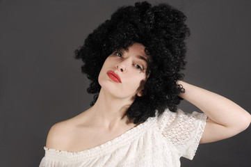 Funny young woman is wearing a black curly wig.