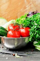 
Fresh juicy ripe summer useful vegetables and greens, red tomatoes , cucumbers , cabbage , lettuce , basil , parsley , dill and salt and spices on a dark wooden background