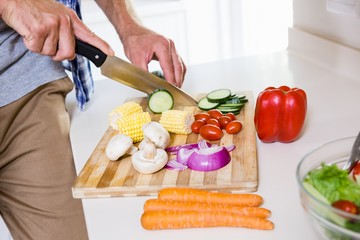 Mid-section of man chopping vegetable in kitchen