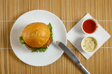 Big beef steak burger with vegetables and herbs on rustic wooden background