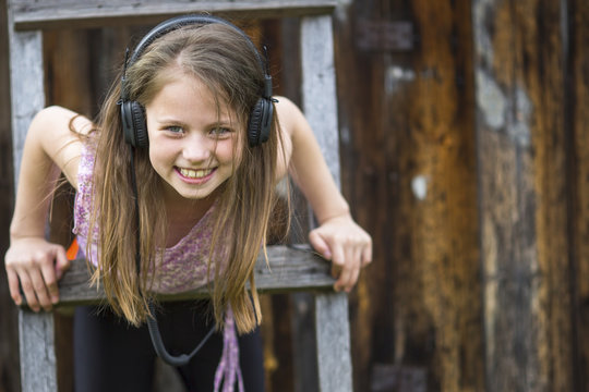 Little happy girl with headphones outdoors.