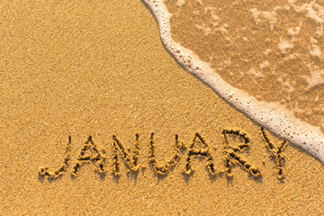 January - written by hand on a golden beach sand.