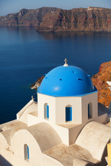 Fototapeta na wymiar Blue dome church in Oia, Santorini, Greece. Sea and volcano on background