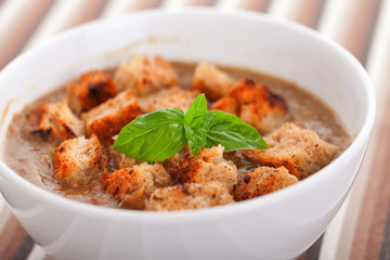 Italian lentil soup with fried bread croutons. Decorated with basil leaf.