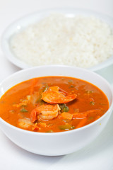 Thai red curry with shrimps, carrots, peppers and onion. Rice on background. Vertical shot