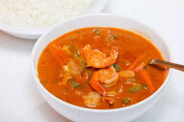Thai red curry with shrimps, carrots, peppers and onion. Rice on background. Horizontal shot