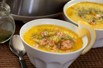 Fish soup from salmon, potatoes, leek and sour cream. Topped with dill. Horizontal shot, slow cooker behind.