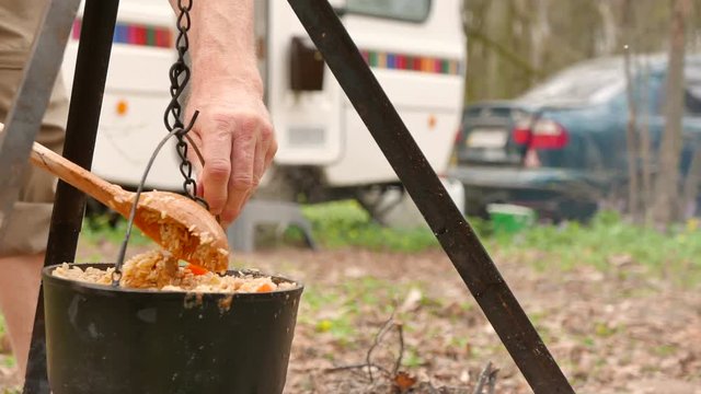 4K shot. Cooking  outdoors in caravan, trailer. Pilaf  close up in wood campfire