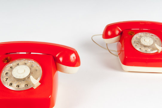 Retro orange telephone with rotary dial on white