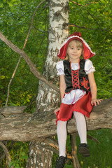 little girl dressed as Little Red Riding Hood in the spring forest