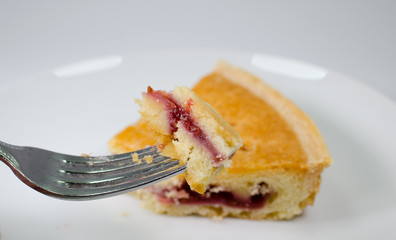 Mouthful of bakewell tart on fork with slice in background