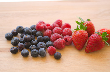 Blueberries, raspberries and strawberries on a wooden background