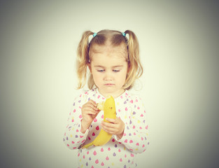 Little girl eating a fresh banana.