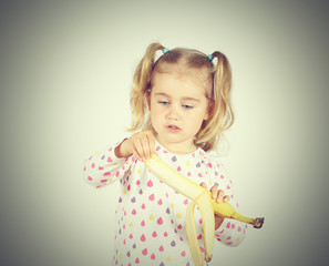 Little girl eating a fresh banana.