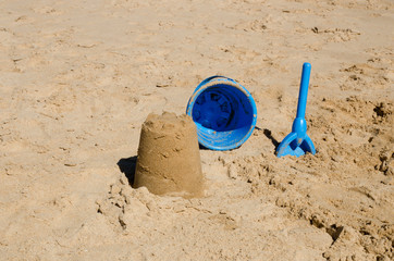 Fototapeta na wymiar Sandcastle, bucket and spade on beach