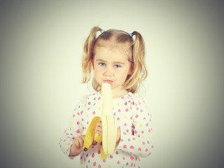 Little girl eating a fresh banana.