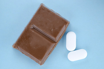 Chocolate triggers migraine headaches concept with piece of chocolate and two painkiller tablets