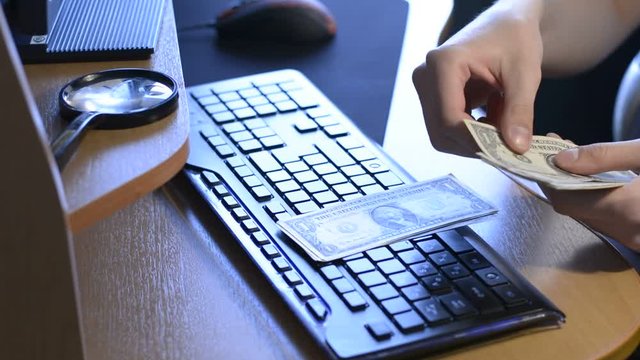 The man in the office counting money at the computer table