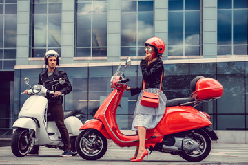 Male and female having fun on moto scooters. - obrazy, fototapety, plakaty