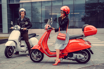 Male and female having fun on moto scooters.