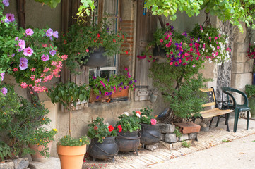 Fototapeta na wymiar A french cottage with lots of hanging baskets, plants and flower pots