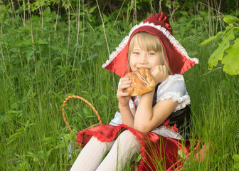 little girl dressed as Little Red Riding Hood in the spring forest