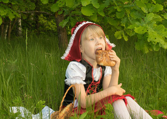 little girl dressed as Little Red Riding Hood in the spring forest