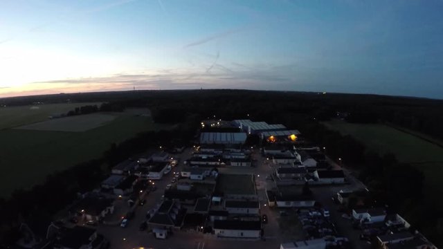 Drone aerial flight at night sundown over a trailerpark trailer park dark dusk dawn operation showing the trailers small lights and some people from park below hanging around helicopter bird eye view