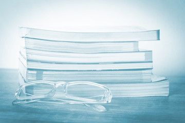 Books and glasses on wooden table and with vintage background.