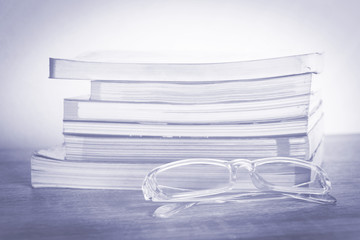 books and glasses on wooden table with vintage background