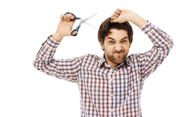 Portrait of handsome angry young man cutting hair with scissors