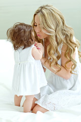 Happy mother with her funny baby on the bedroom