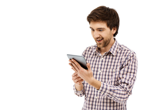 Portrait of handsome smiling young man, using tablet.