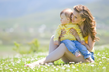 Mother with little son in a flower field 