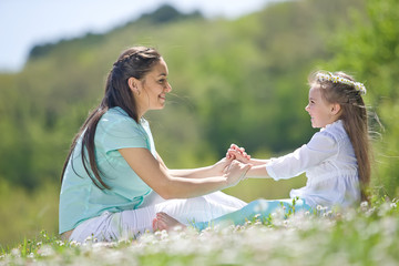 Mother with kid are resting on the nature on camomile field