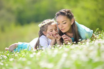 Mother with kid are resting on the nature on camomile field