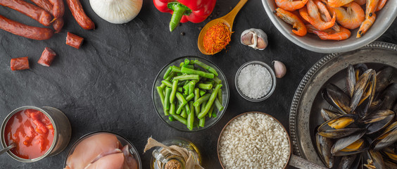 Ingredients for paella on the dark stone table wide screen