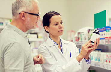 Fototapeta premium pharmacist showing drug to senior man at pharmacy