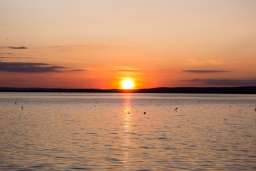 Picturesque view of a beautiful sunset over a river. Cloudy colorful sky.