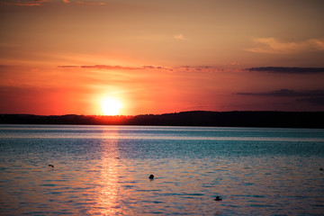 Obraz premium Picturesque view of a beautiful sunset over a river. Cloudy colorful sky.