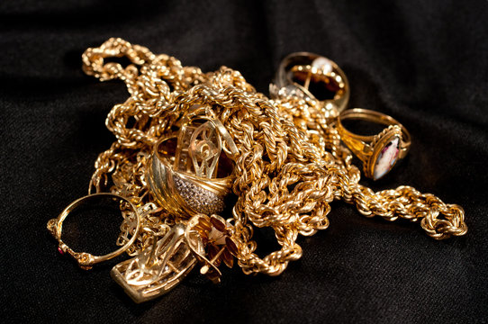 scrap gold jewellery including chains, bracelets and rings on a black background