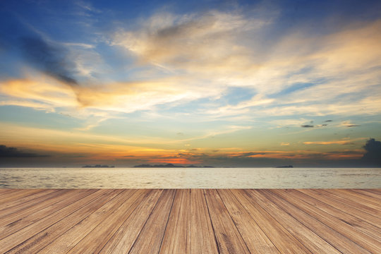 Fototapeta Perspective of wood terrace against beautiful seascape at sunset